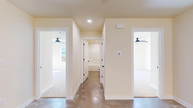 hall with finished concrete flooring, baseboards, and recessed lighting