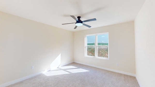 unfurnished room with a ceiling fan, light carpet, and baseboards