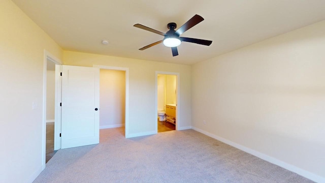 unfurnished bedroom with light colored carpet, a ceiling fan, baseboards, a spacious closet, and ensuite bath