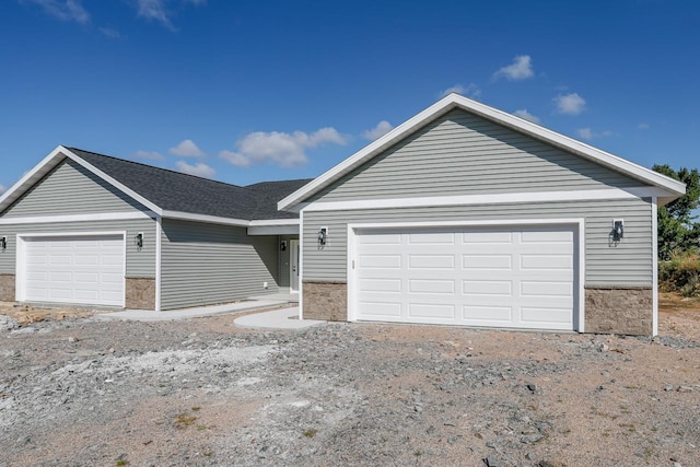 ranch-style home with an attached garage and dirt driveway