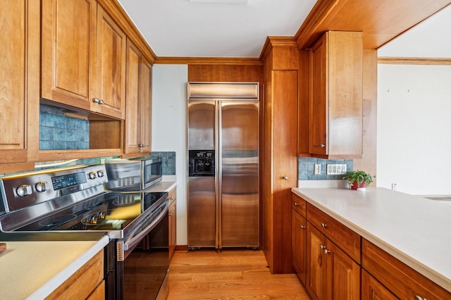 kitchen with appliances with stainless steel finishes, light hardwood / wood-style floors, and tasteful backsplash