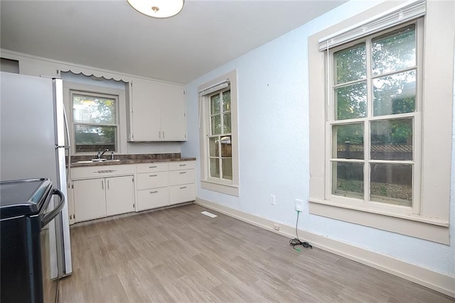 kitchen featuring light hardwood / wood-style flooring, white cabinets, stainless steel electric range, and sink