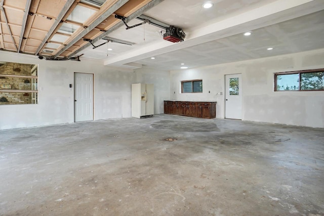 garage with a garage door opener and white refrigerator with ice dispenser