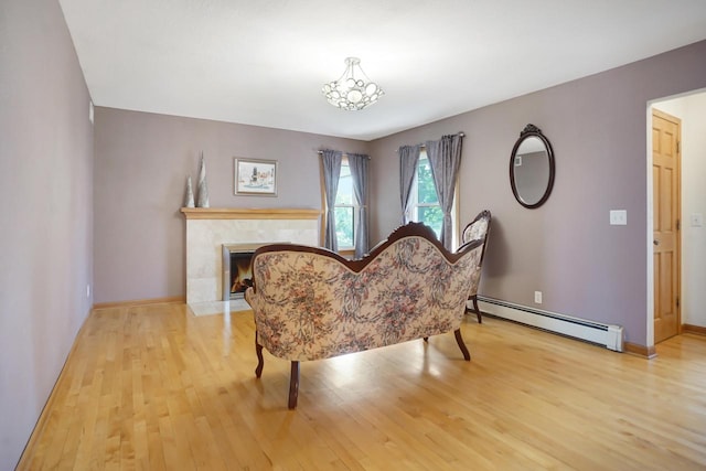 living area with a tiled fireplace, light hardwood / wood-style floors, and baseboard heating