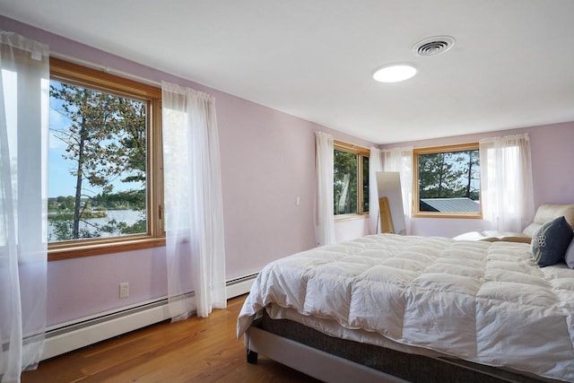 bedroom with a baseboard radiator and hardwood / wood-style flooring