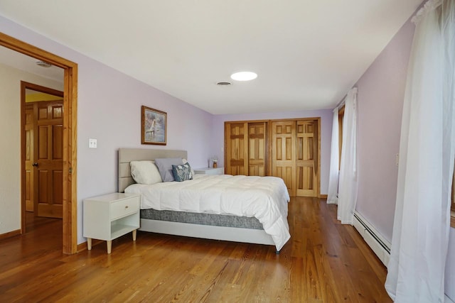 bedroom with a baseboard heating unit and wood-type flooring