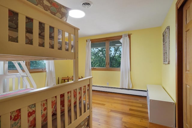 bedroom with baseboard heating and hardwood / wood-style flooring