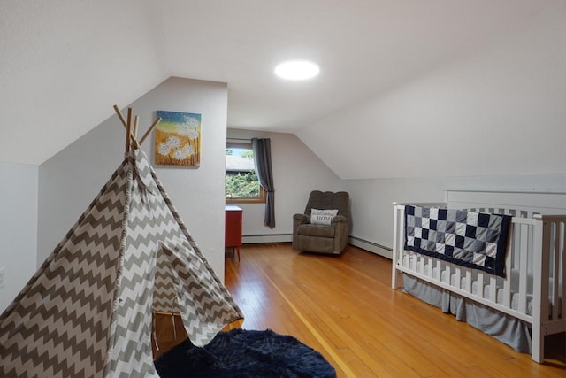 bedroom with baseboard heating, a crib, lofted ceiling, and hardwood / wood-style floors