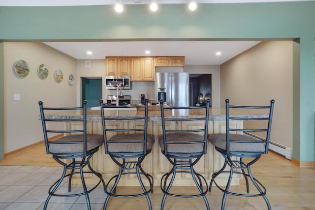 kitchen with appliances with stainless steel finishes, a breakfast bar area, and light hardwood / wood-style flooring