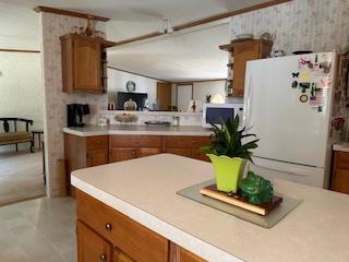 W4706 29th St, Necedah, WI 54646 - kitchen with white appliances, brown cabinetry, wallpapered walls, and light countertops