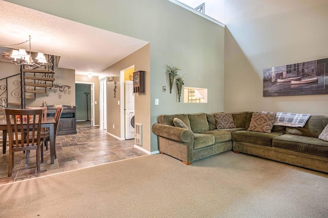 living room featuring washer / clothes dryer, vaulted ceiling, carpet floors, a textured ceiling, and a chandelier