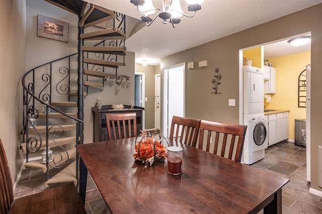 dining area with an inviting chandelier, a textured ceiling, and stacked washing maching and dryer