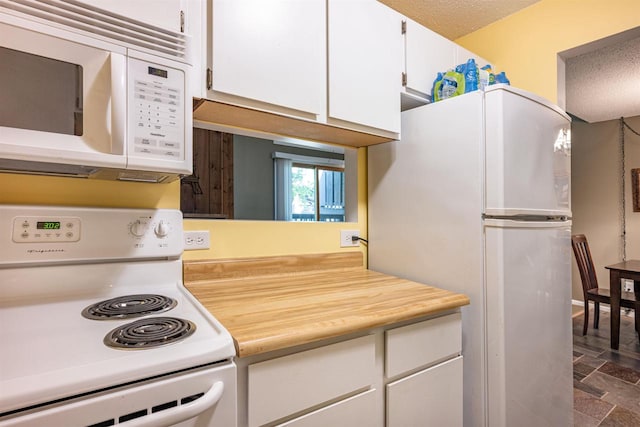 kitchen featuring white appliances, a textured ceiling, and white cabinetry