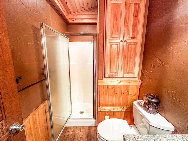 bathroom featuring lofted ceiling, toilet, wooden walls, hardwood / wood-style floors, and an enclosed shower