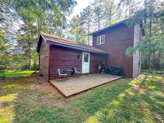 rear view of property featuring a lawn and a deck