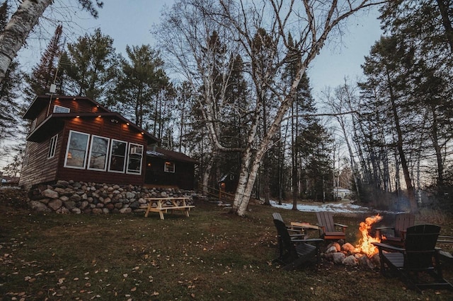 back of house featuring a yard and an outdoor fire pit