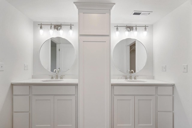 full bath featuring a sink, visible vents, and two vanities