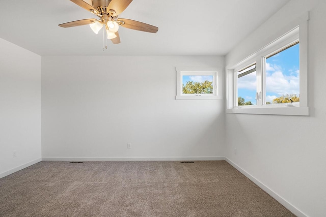 carpeted spare room featuring visible vents, baseboards, and a ceiling fan