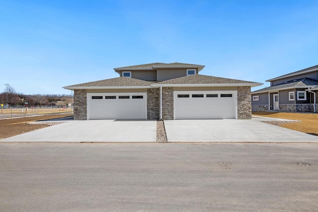 prairie-style home with stone siding, concrete driveway, an attached garage, and a shingled roof