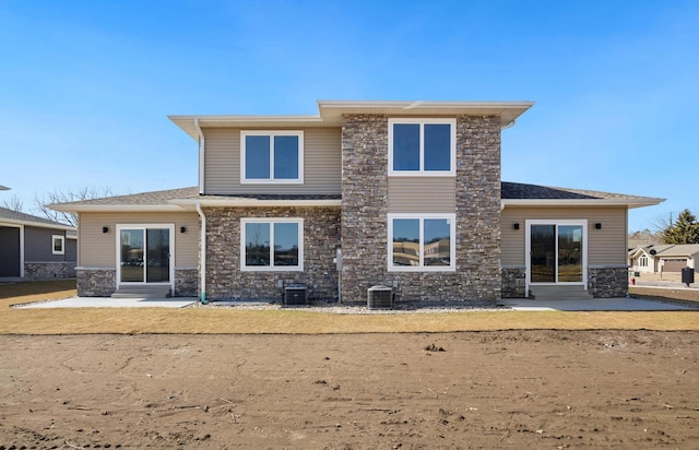 back of house featuring a patio area, stone siding, central air condition unit, and a shingled roof