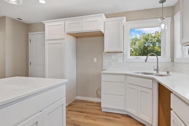 kitchen featuring a sink, backsplash, white cabinets, and light countertops