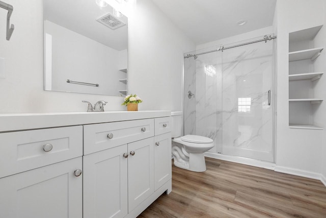 bathroom featuring wood-type flooring, vanity, a shower with shower door, and toilet