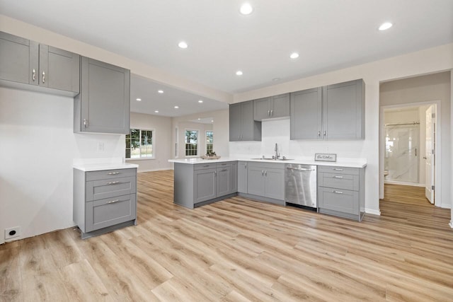 kitchen with gray cabinetry, light hardwood / wood-style floors, kitchen peninsula, stainless steel dishwasher, and sink