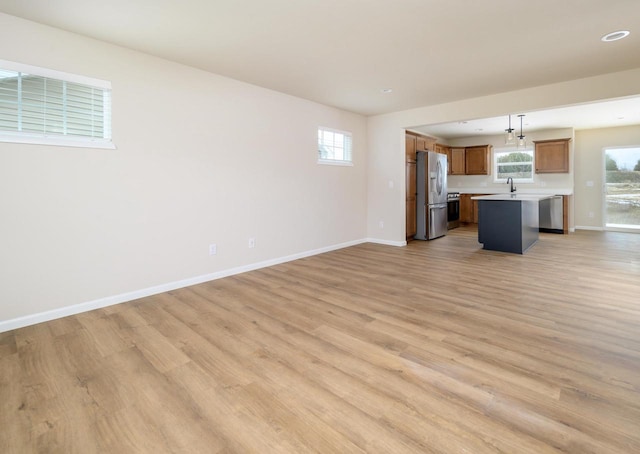 unfurnished living room featuring sink, a wealth of natural light, and light hardwood / wood-style flooring