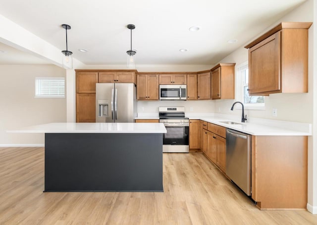 kitchen with stainless steel appliances, sink, decorative light fixtures, light hardwood / wood-style floors, and a kitchen island