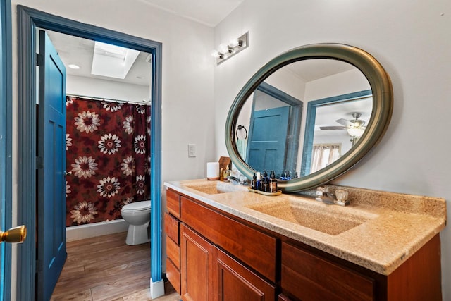 bathroom featuring wood-type flooring, vanity, toilet, and a skylight