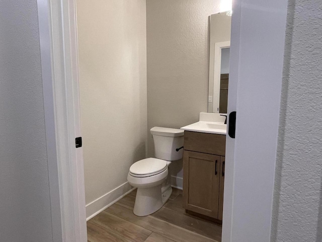 bathroom with hardwood / wood-style floors, vanity, and toilet