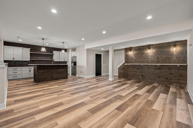 unfurnished living room with light hardwood / wood-style flooring and wood walls