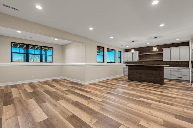 kitchen with white cabinetry, a center island, light hardwood / wood-style floors, and hanging light fixtures