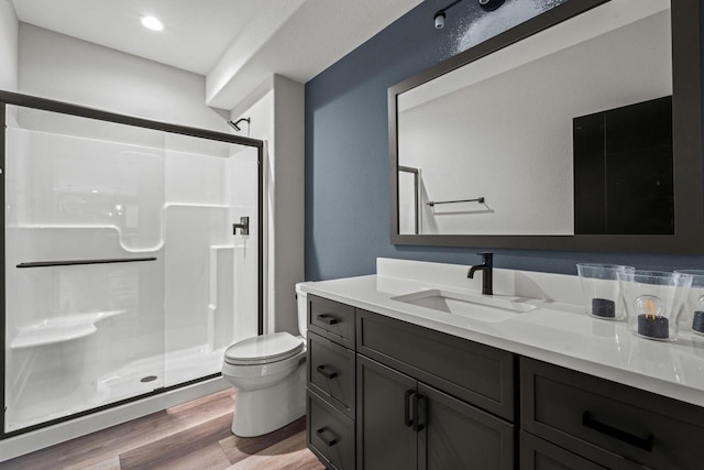 bathroom with wood-type flooring, toilet, a shower with shower door, and vanity