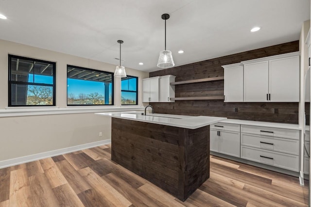 kitchen with pendant lighting, plenty of natural light, an island with sink, and white cabinets