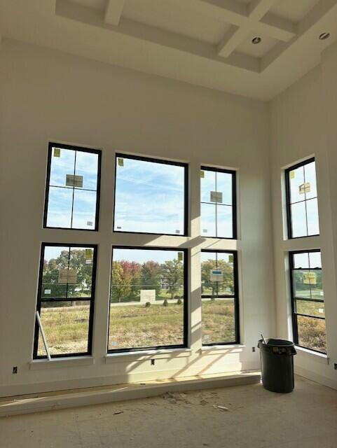 interior space with coffered ceiling, beam ceiling, and a high ceiling