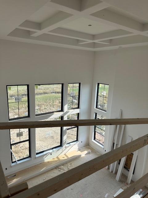 stairway featuring coffered ceiling, beam ceiling, and a wealth of natural light