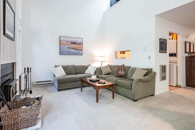 carpeted living room featuring a towering ceiling and a baseboard heating unit