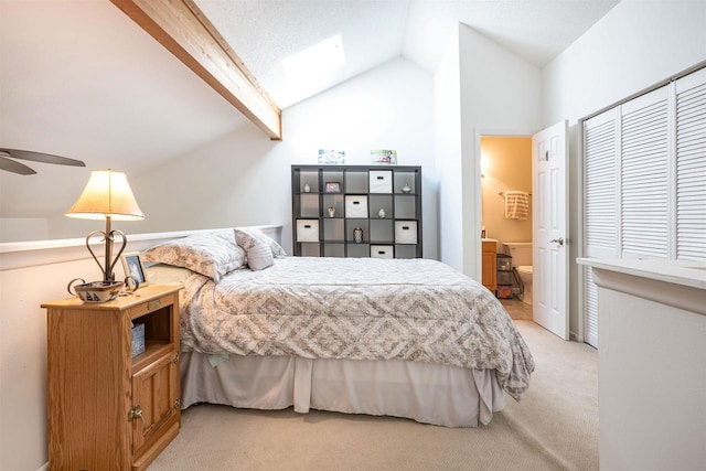 carpeted bedroom featuring lofted ceiling with beams, ensuite bath, and ceiling fan