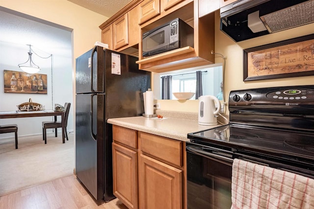 kitchen featuring pendant lighting, light wood-type flooring, and black appliances