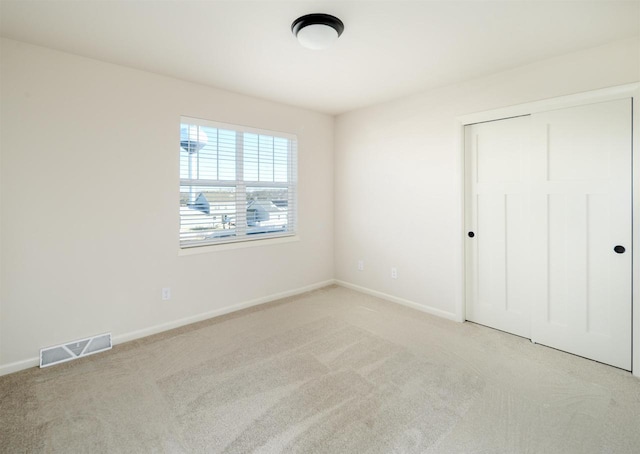 unfurnished bedroom featuring light colored carpet and a closet