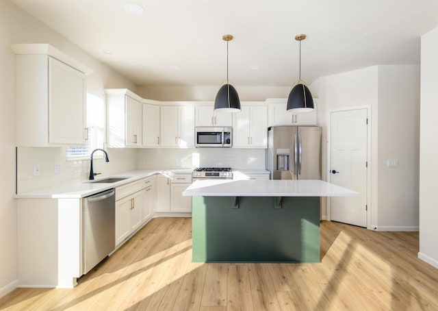 kitchen with stainless steel appliances, hanging light fixtures, a kitchen island, sink, and white cabinetry