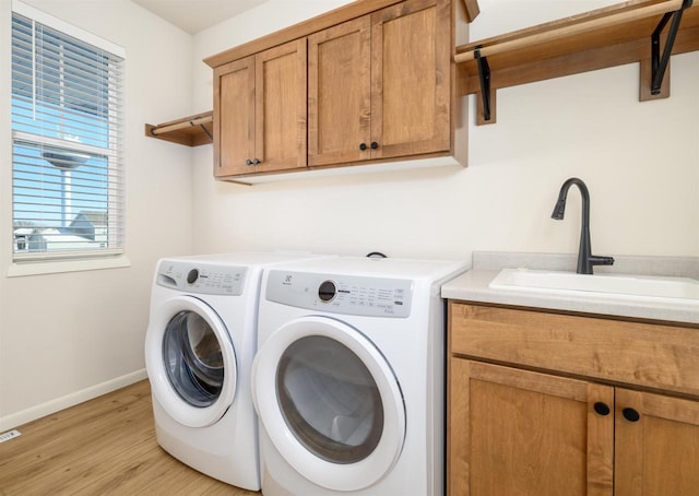 washroom with sink, light wood-type flooring, cabinets, and independent washer and dryer