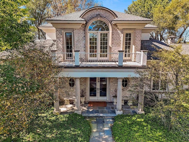 view of front of house featuring a balcony and french doors