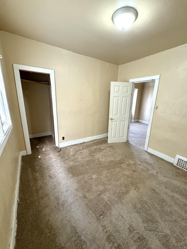 unfurnished bedroom with dark colored carpet and a closet