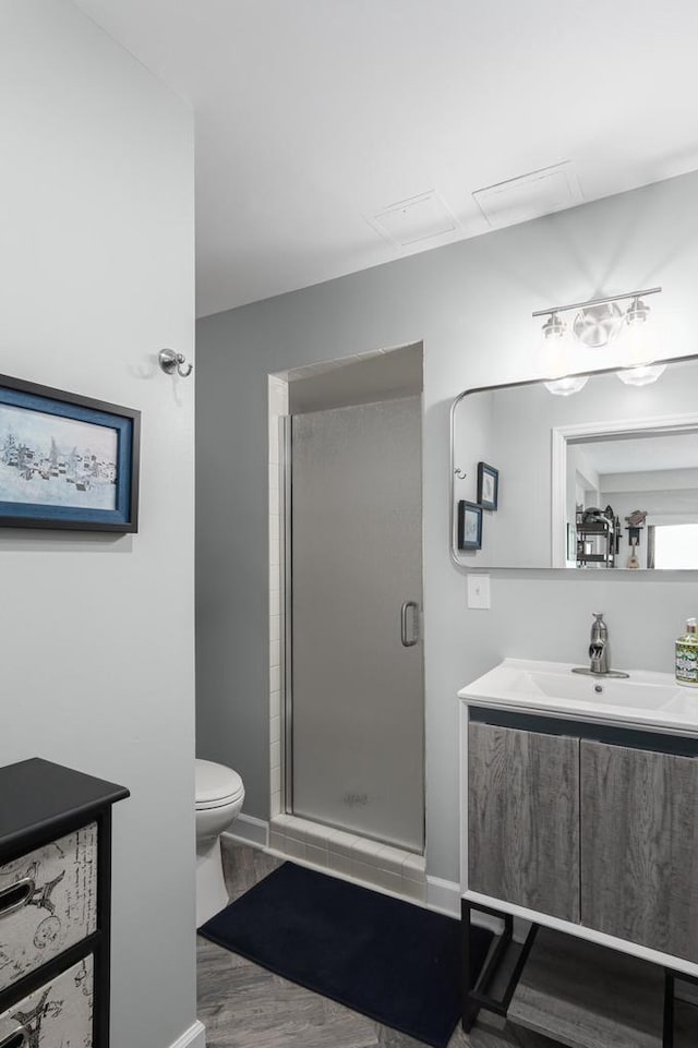 bathroom with wood-type flooring, vanity, toilet, and a shower with door