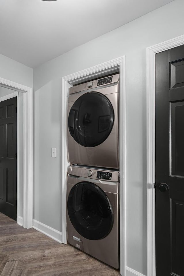 clothes washing area featuring hardwood / wood-style floors and stacked washing maching and dryer