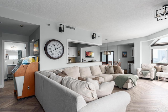 living room featuring an inviting chandelier, a textured ceiling, and parquet floors