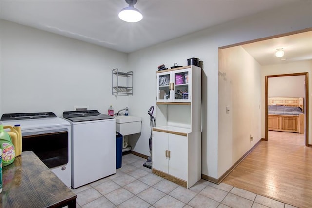 laundry area with separate washer and dryer, light wood-type flooring, and sink