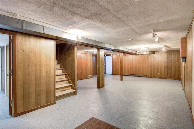 basement with a textured ceiling, wood walls, and a baseboard radiator